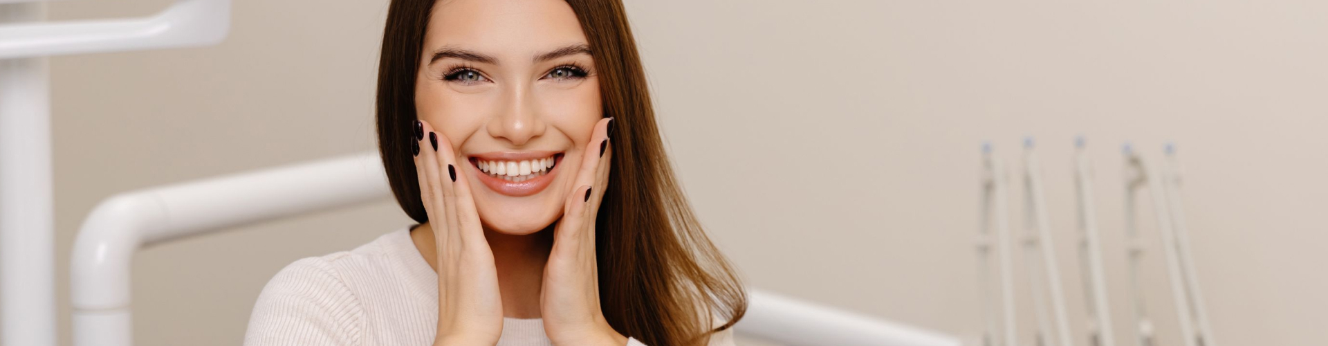 Woman smiling with hands on her cheeks, showing a bright, straight smile.